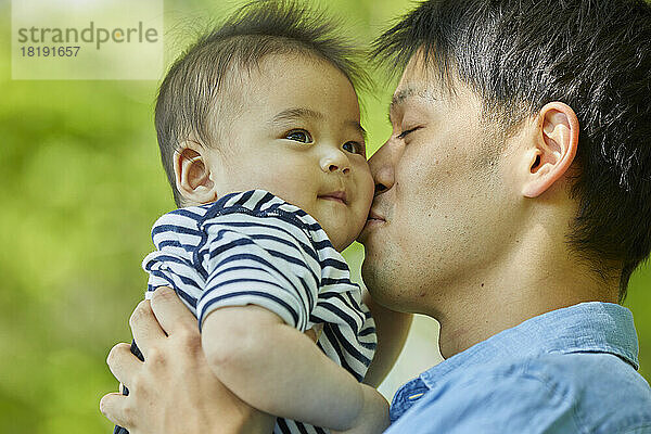 Japanischer Vater küsst Baby