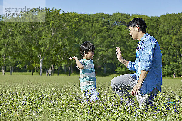 Japanisches Elternteil und Kind geben ein High Five