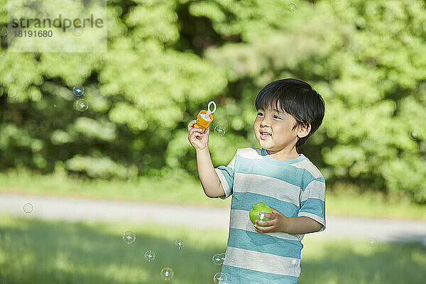 Japanischer Junge spielt mit Blasen