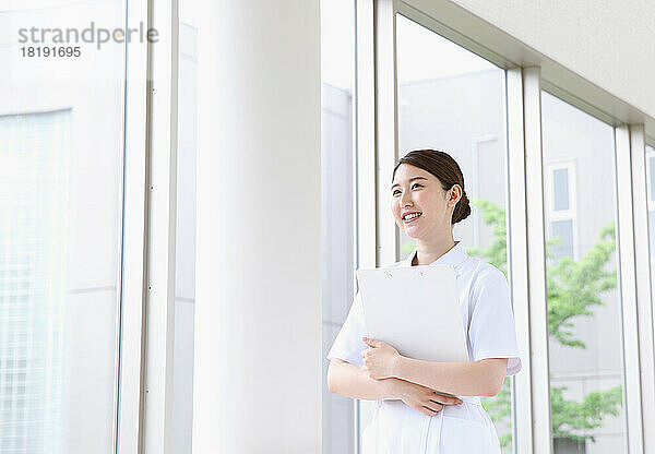 Junge japanische Krankenschwester geht durch den Flur