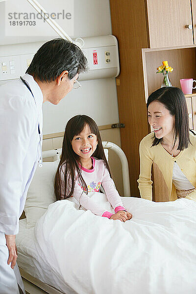 Japanisches Mädchen wird von einem Arzt in einem Krankenzimmer untersucht