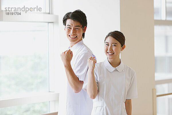 Lächelnde junge japanische Krankenschwestern posieren im Flur