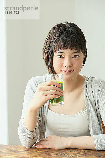 Junge Japanerin trinkt grünen Smoothie