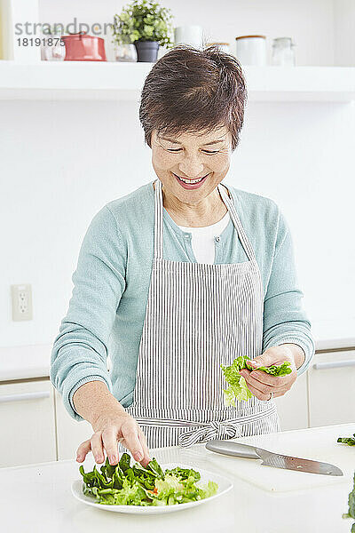 Japanische Seniorin serviert Salat