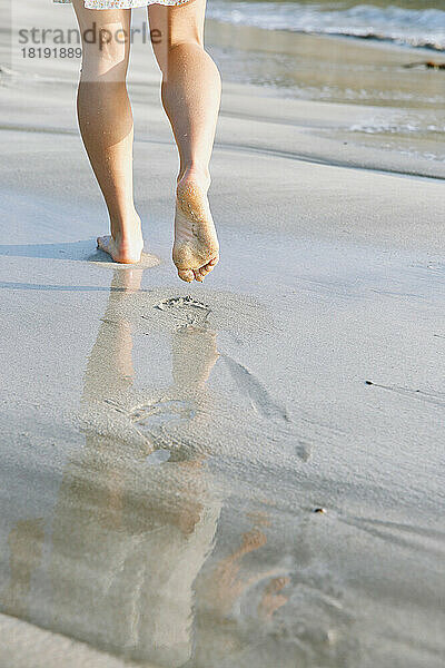 Die Füße einer jungen Frau  die am Strand spaziert