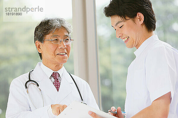 Ein japanischer Arzt und ein junger Krankenpfleger unterhalten sich im Flur