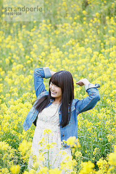 Junge Japanerin atmet tief in einem Blütenfeld ein