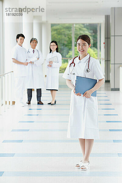 Lächelnde junge Krankenschwester und Ärzteteam im Flur