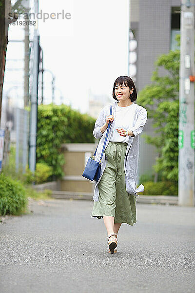 Junge Japanerin läuft am Bahnzaun entlang