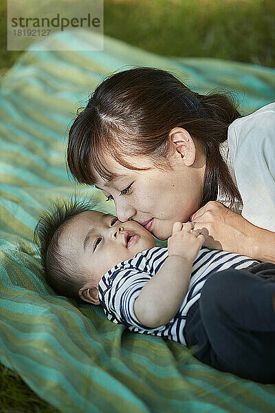 Japanische Mutter kuschelt mit ihrem Baby