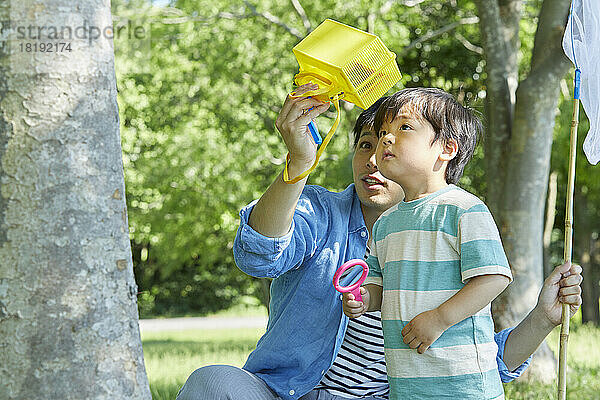 Japanische Eltern und Kinder sammeln Insekten