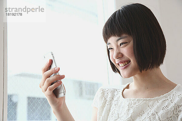 Junge Japanerin bedient ein Mobiltelefon