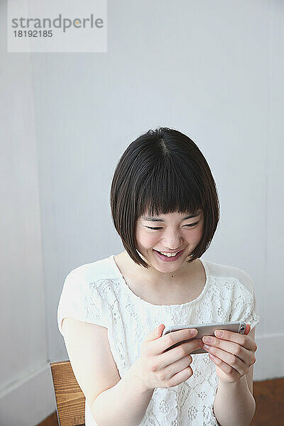 Junge Japanerin schaut auf ihr Mobiltelefon