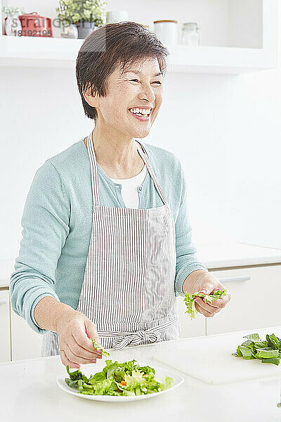 Japanische Seniorin serviert Salat