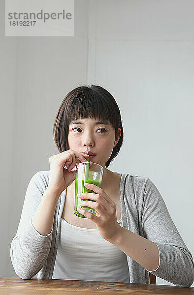 Junge Japanerin trinkt einen grünen Smoothie