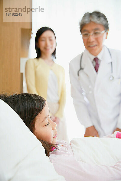 Japanisches Mädchen wird von einem Arzt in einem Krankenzimmer untersucht