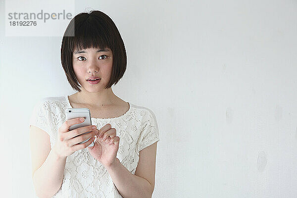Junge Japanerin bedient ein Mobiltelefon