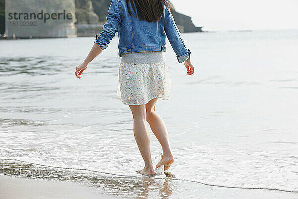 Die Füße einer jungen Japanerin  die am Strand spaziert