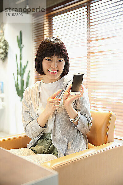 Junge Japanerin benutzt Mobiltelefon im Schönheitssalon