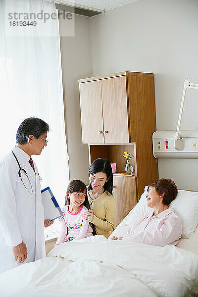 Japanische ältere Frau wird von einem Arzt in einem Krankenzimmer untersucht