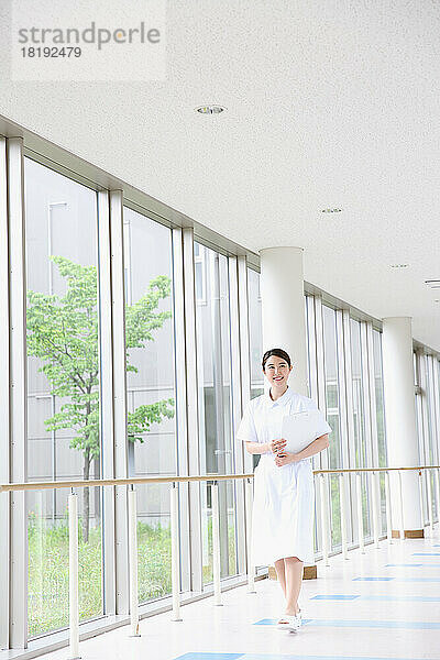 Junge japanische Krankenschwester geht durch den Flur