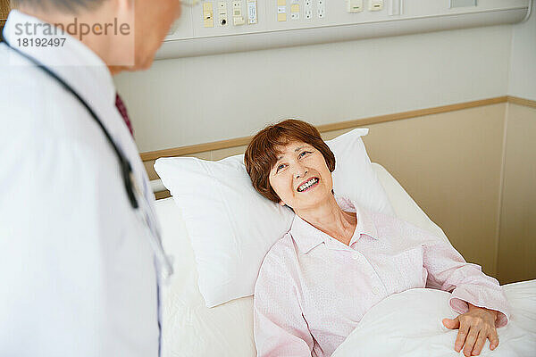 Japanische ältere Frau wird von einem Arzt in einem Krankenzimmer untersucht
