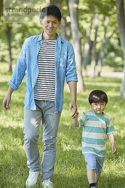 Japanische Eltern und Kinder gehen im frischen Grün spazieren
