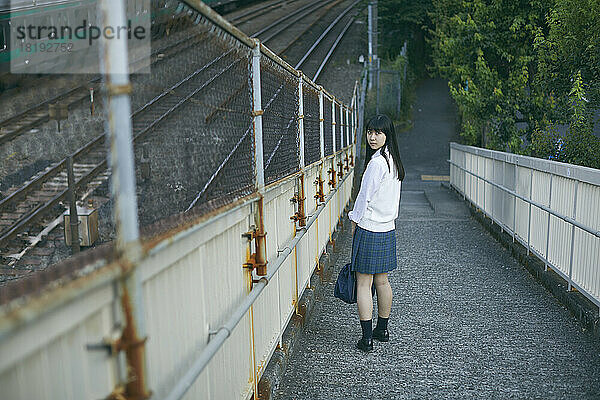 Japanisches Highschool-Mädchen auf einer Fußgängerbrücke