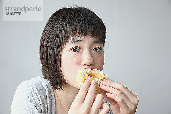 Junge Japanerin isst einen Donut