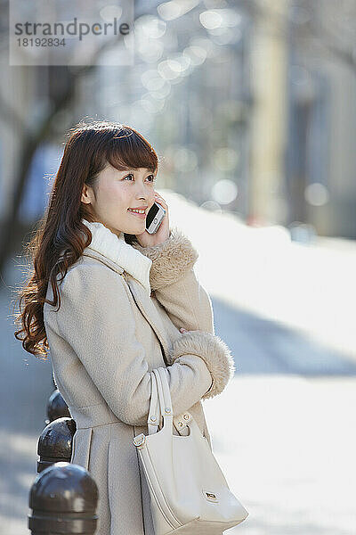 Japanerin spricht mit einem Mobiltelefon