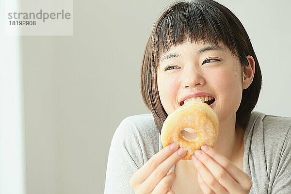 Junge Japanerin isst einen Donut