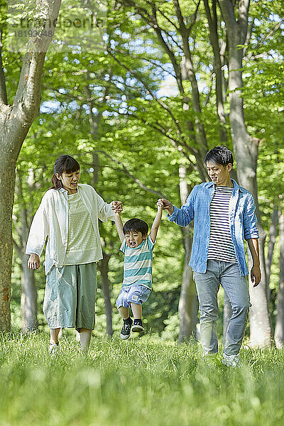 Japanische Familie hält Händchen im frischen Grün