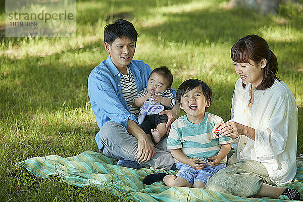 Japanische Familie entspannt auf dem Rasen