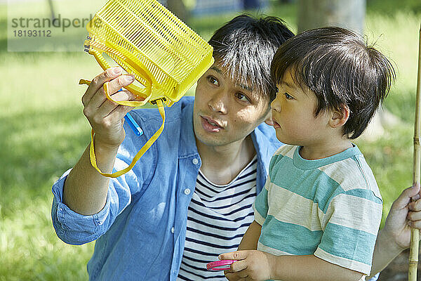 Japanische Eltern und Kinder sammeln Insekten