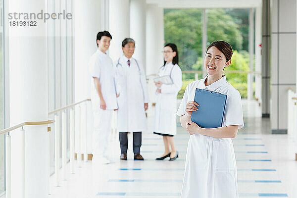 Lächelnde junge Krankenschwester und Ärzteteam im Flur