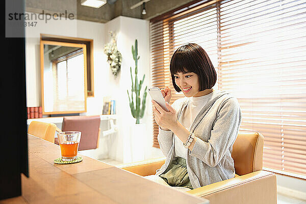 Junge Japanerin benutzt Mobiltelefon im Schönheitssalon