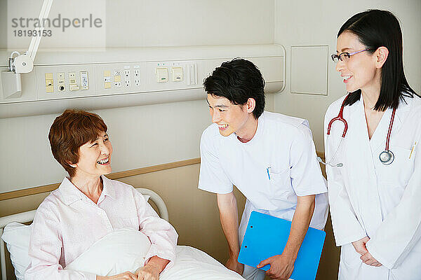 Ältere Frau wird von einem Arzt und einer Krankenschwester in einem Krankenzimmer untersucht