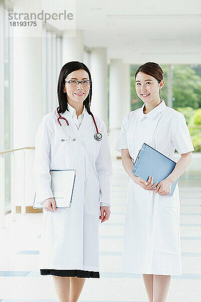 Lächelnder Arzt und junge Krankenschwester im Flur