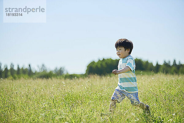 Japanischer Junge läuft auf dem Feld