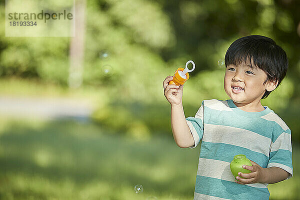 Japanischer Junge spielt mit Blasen