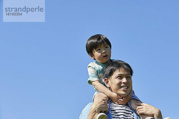 Japanischer Vater trägt sein Kind auf seinen Schultern