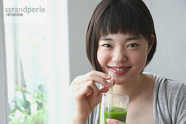 Junge Japanerin trinkt einen grünen Smoothie
