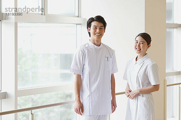 Lächelnde japanische junge Krankenschwester im Flur
