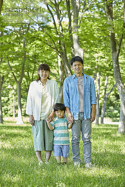 Japanische Familie hält Händchen im frischen Grün