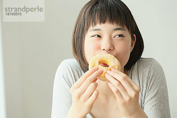 Junge Japanerin isst einen Donut