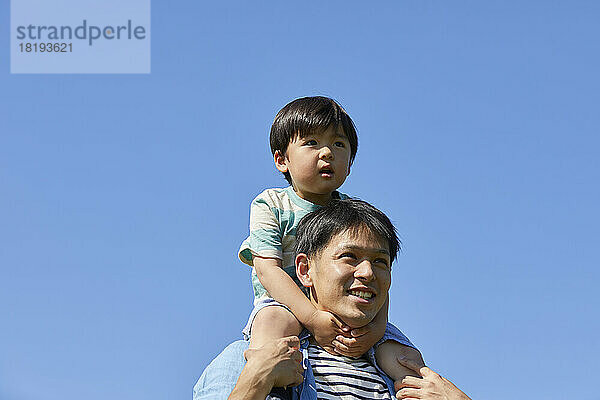 Japanese father carrying his child on his shoulders