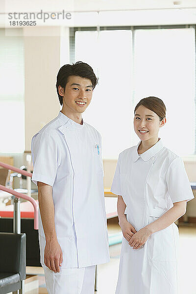Lächelnde junge japanische Krankenschwestern in der Reha-Einrichtung