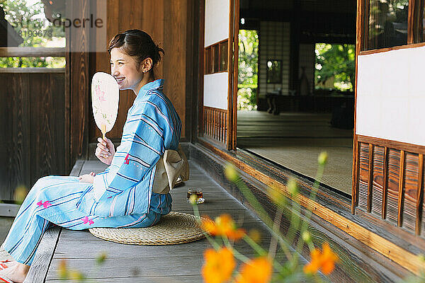 Japanerin in Yukata kühlt sich auf der Veranda ab