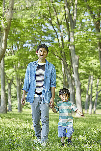 Japanische Eltern und Kinder halten Händchen im frischen Grün