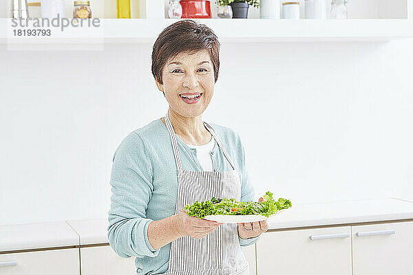 Ältere japanische Frau trägt eine Portion Salat